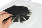Eine Hand hält ein schwarzes, rechteckiges Stück Stoff vor einer weißen, ventilartigen Abdeckung.
