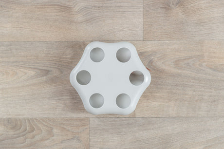 Weiße, sechseckige Plastikform mit runden Vertiefungen, liegt auf einem hellen Holzfußboden.