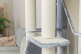 Kratzturm aus hellem Stoff mit grauen Plüscheinfassungen vor Sofa im Wohnzimmer.