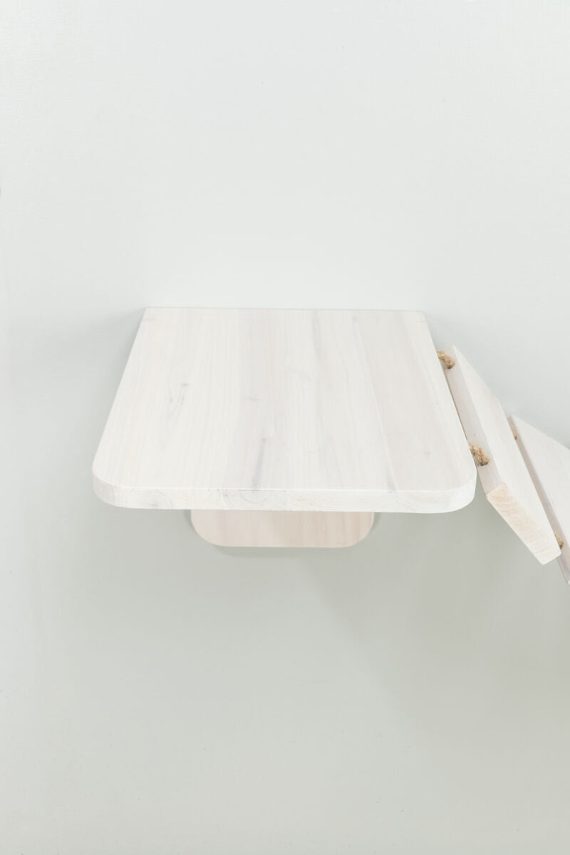 Eine helle, hölzerne Wandablage mit abgerundeten Ecken ist an einer weißen Wand befestigt.