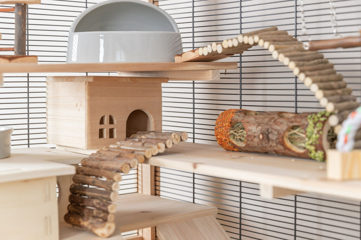 Holzhaus und Rampen in einem Käfig mit Tunnel aus Zweigen und Heu, Schalen und Brücke auf zwei Ebenen.