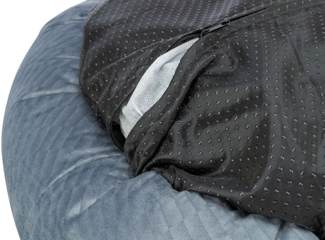 Ein graues, gestepptes Material mit einer schwarzen, perforierten Abdeckung, die teilweise geöffnet ist und weißen Stoff zeigt.