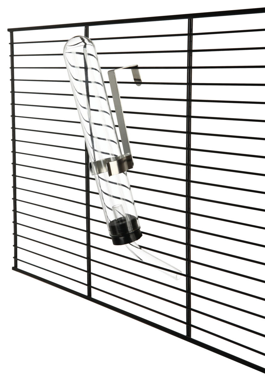 Ein transparentes Trinkfläschchen mit Metallhalterung ist an einem schwarzen Gitter befestigt.