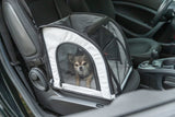 Kleiner Hund sitzt in schwarzer und weißer Transporttasche auf Autositz.