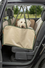 Ein Hund sitzt in einer beigen Autoschondecke auf dem Rücksitz eines Autos.