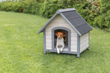Kleiner Hund sitzt in einer Hundehütte auf einer grünen Wiese.