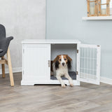 Hund sitzt in einem offenen, weißen Schrank mit Gittertür, der auf hellem Holzboden steht, daneben ein grauer Stuhl.