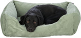 Ein schwarzer Hund liegt in einem grünen, gerippten Hundebett und blickt direkt in die Kamera.