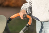 Person in grauem Sweatshirt hält Lenker mit brauner Griffpolsterung.