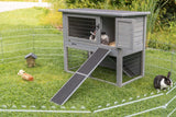 Graues Kaninchengehege mit Rampe und zwei Kaninchen auf grünem Rasen im Freien.