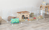 Weißer Laufstall mit Holzhütte, Heu, Wasserflasche, Spielsachen und einem Tier auf Holzfußboden.