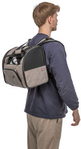 Eine Person trägt einen beige-braunen Rucksack mit schwarzen Netzpanelen auf dem Rücken, seitlich betrachtet.