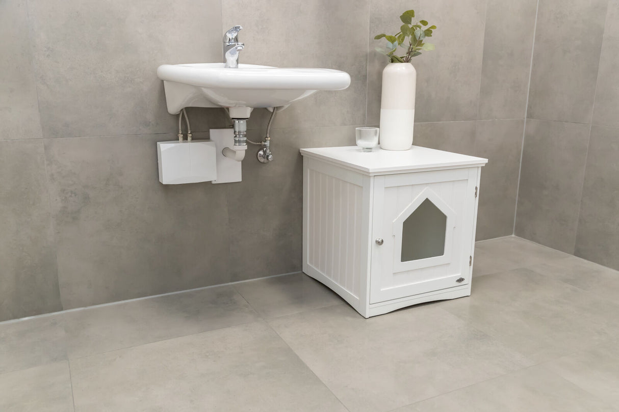 Ein weißes Waschbecken mit Wasserhahn über einer weißen Kommode mit Pflanze und Glas, in einem grau gefliesten Raum.